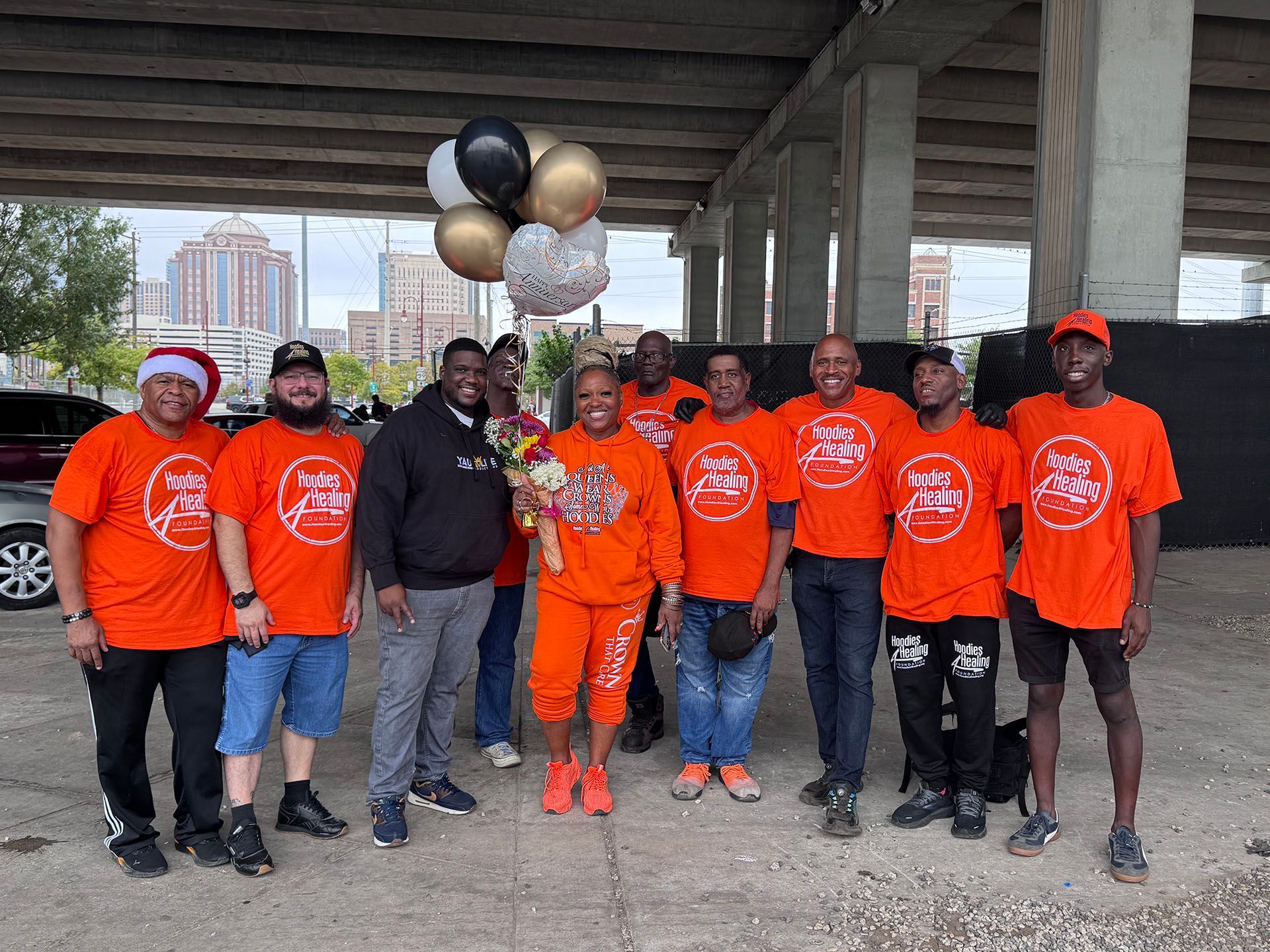 A group of people wearing orange shirts are posing for a picture under a bridge.