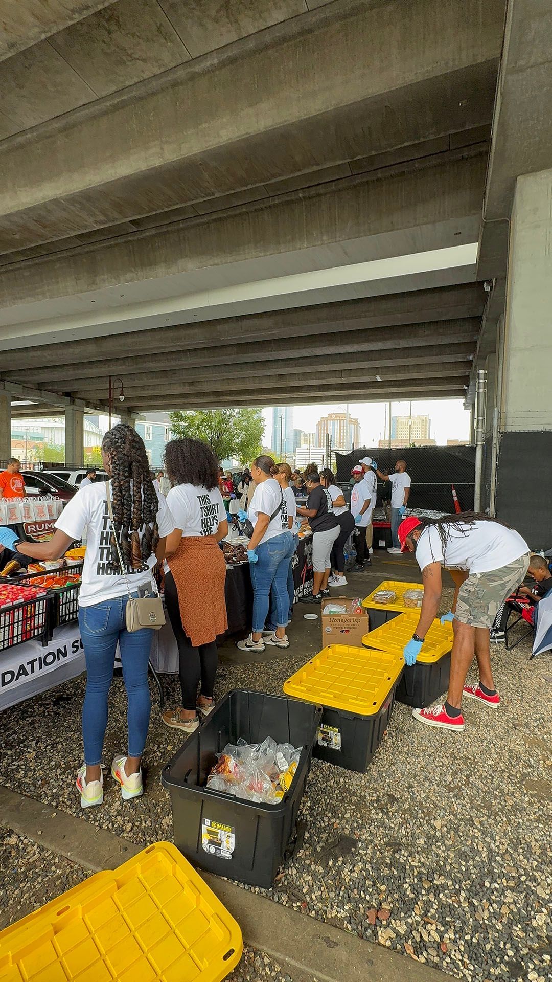 A group of people are standing around a table under a bridge.