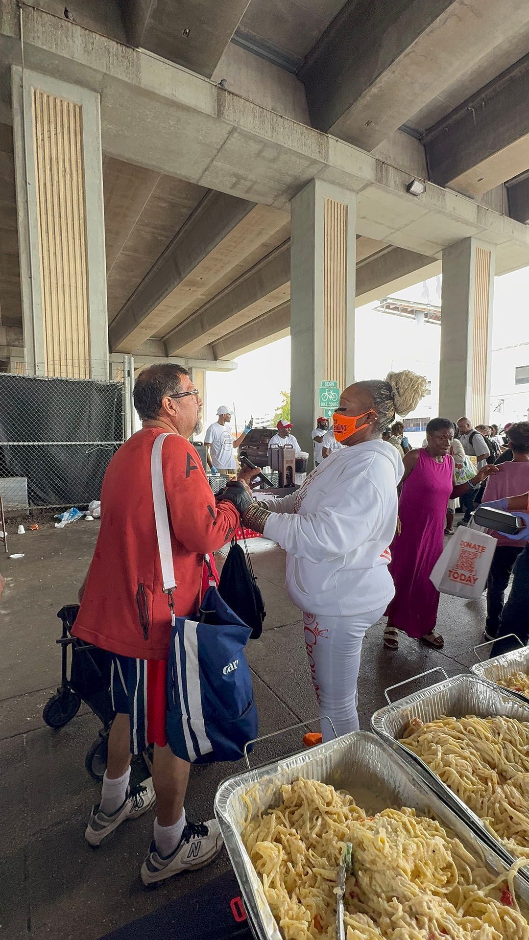 A group of people are standing around a table with containers of food.