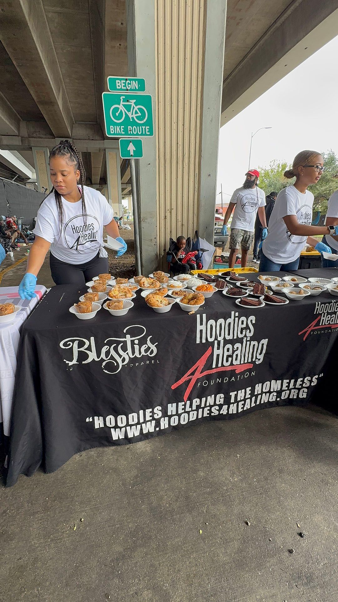 A woman is standing at a table with cupcakes on it.