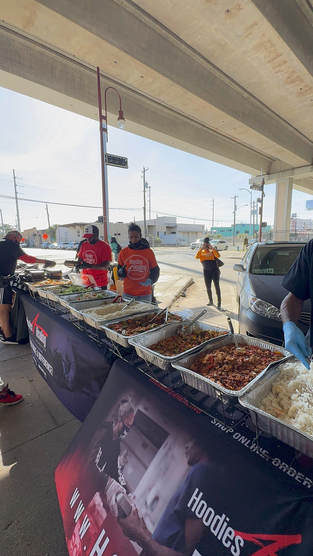 A group of people are standing around a table filled with food.