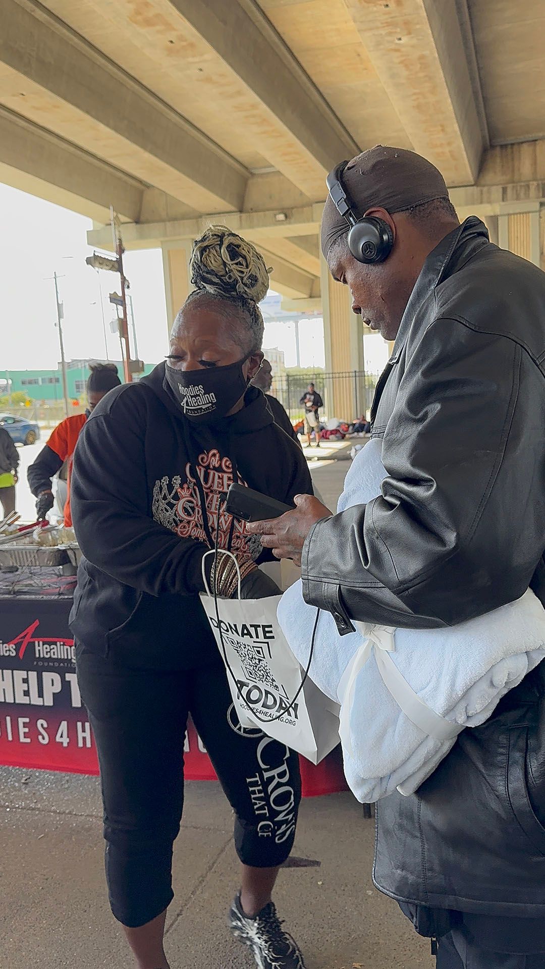 A man wearing headphones is talking to a woman wearing a mask.