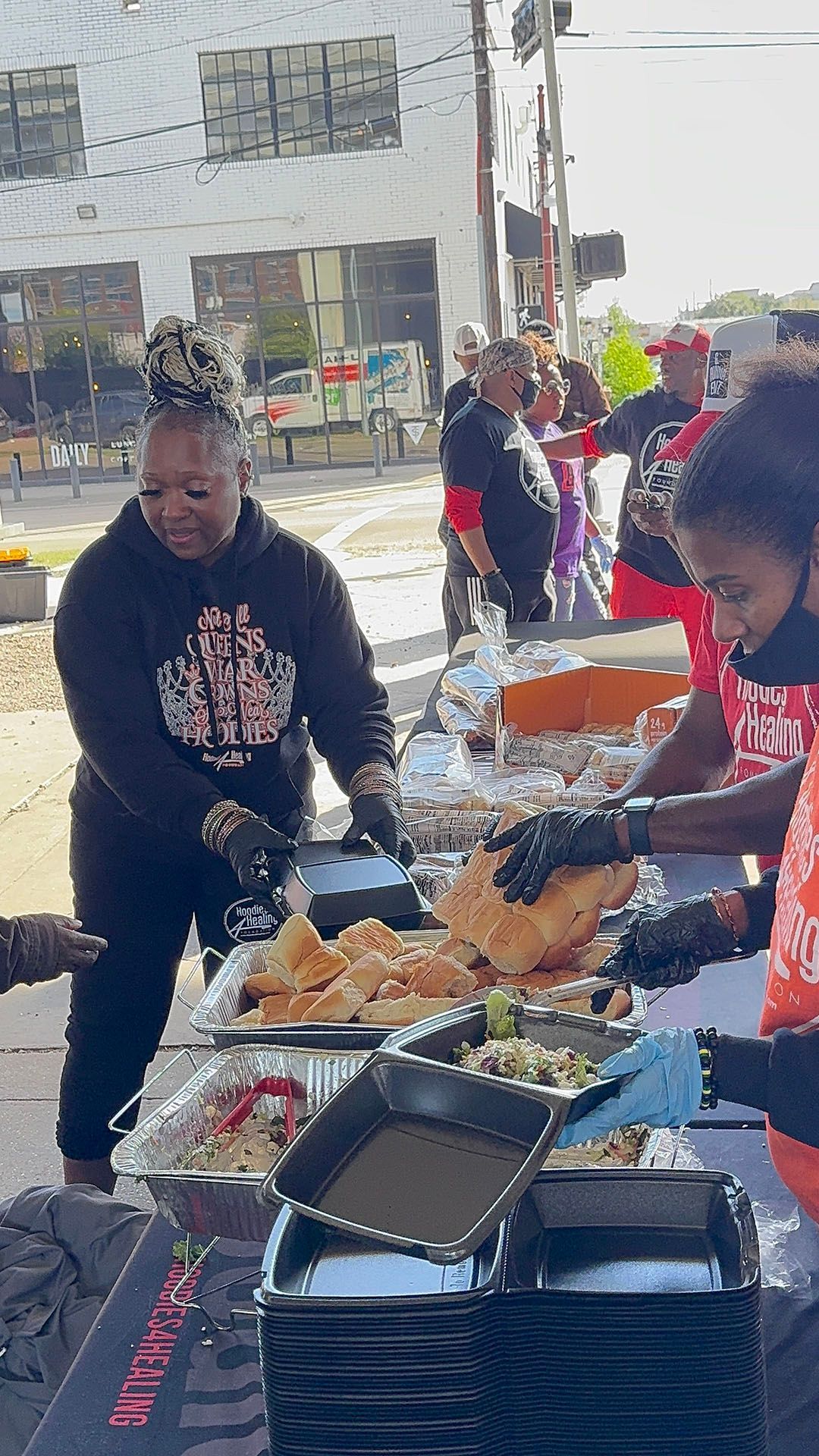 A group of people are standing around a table serving food.