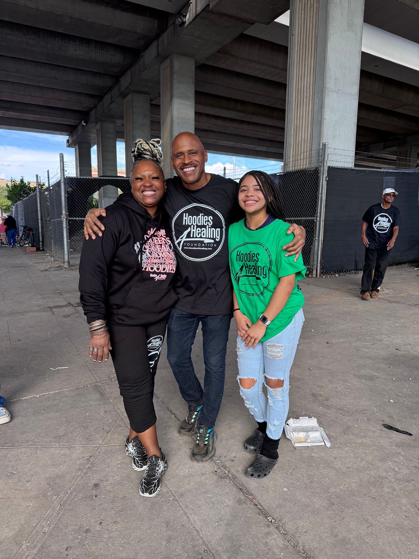 A man and two women are posing for a picture under a bridge.