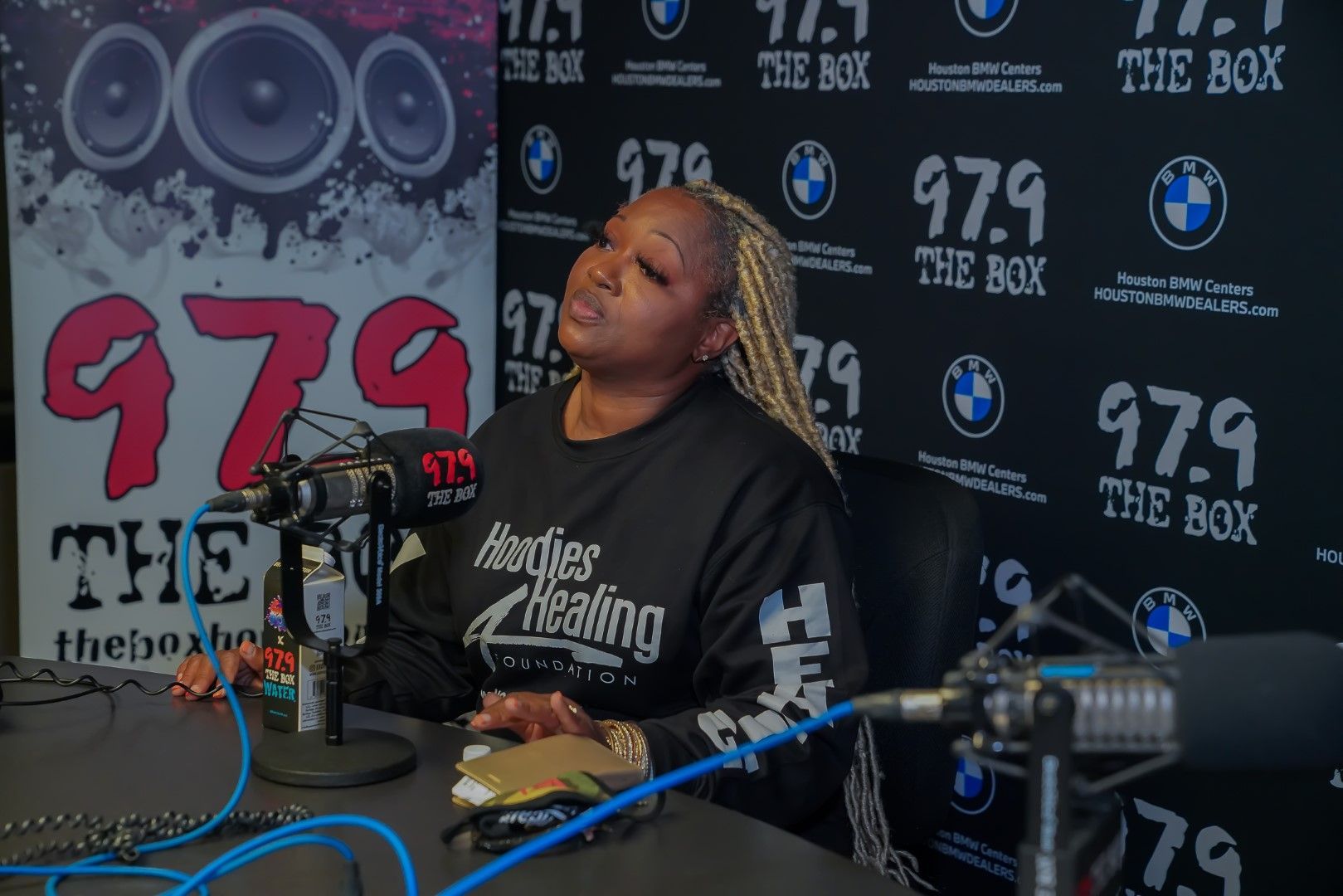 A woman is sitting in front of a microphone at a radio station.