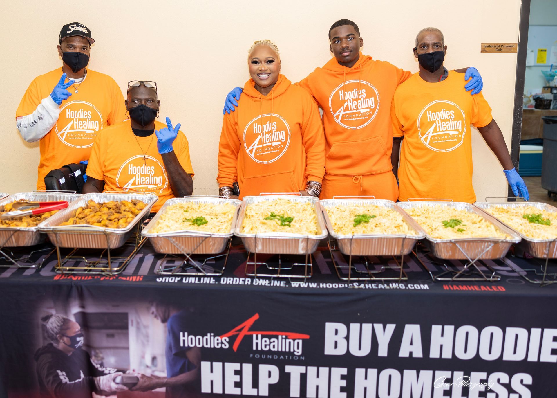 A group of people are standing around a table with trays of food.