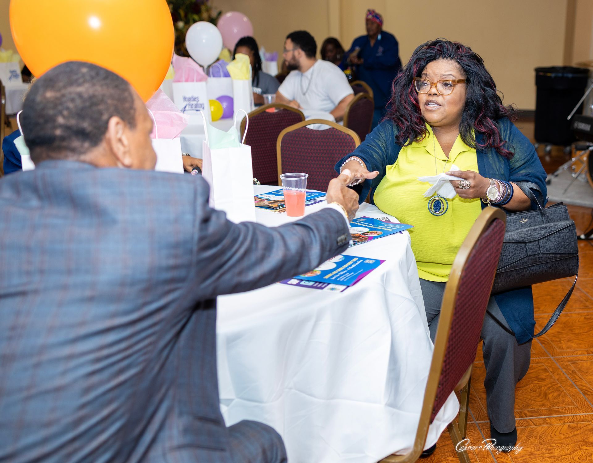 A man in a suit shakes hands with a woman in a yellow shirt