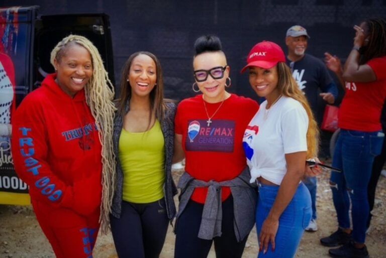 A group of women posing for a picture with one wearing a re/max shirt