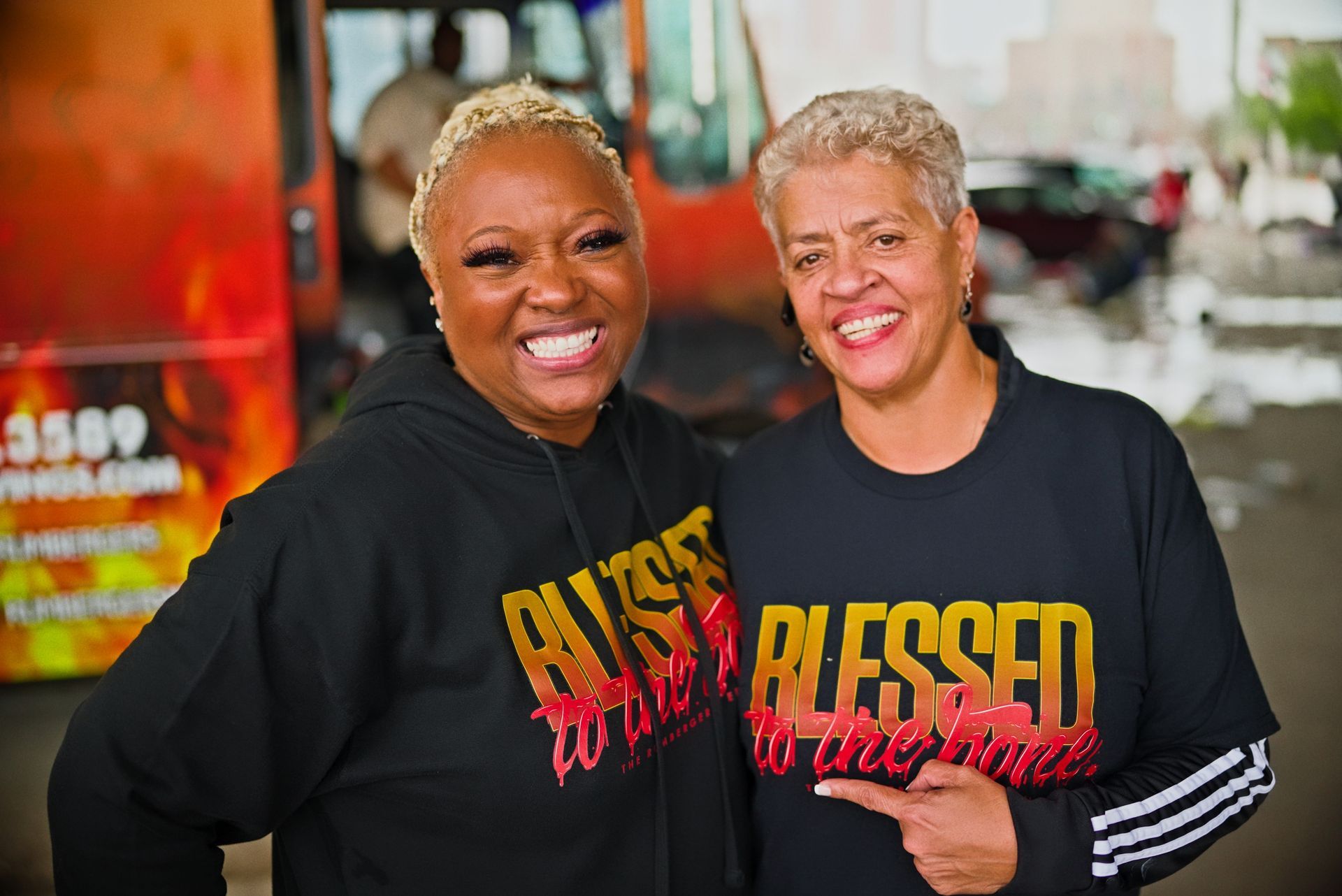 Two women are posing for a picture and one of them is pointing at the camera.