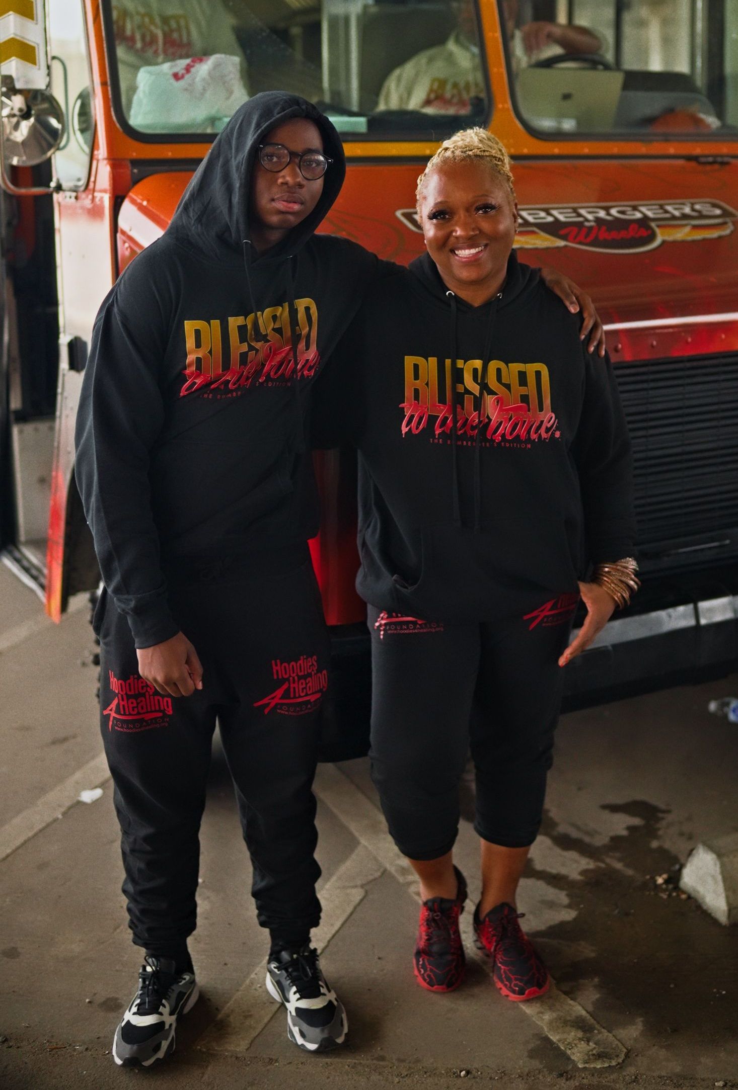 A woman in a red hoodie and red shorts is standing in a parking lot.