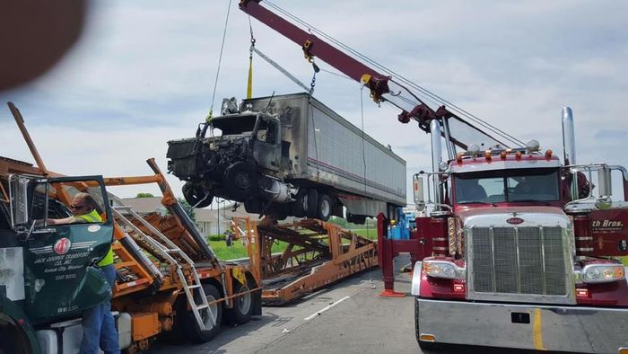 A truck is being towed by a crane on the side of the road. A truck is being towed by a crane on the side of the road.