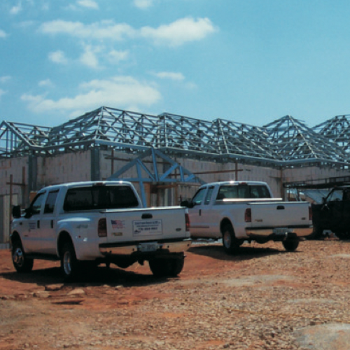 two pickup trucks are parked in front of a building under construction
