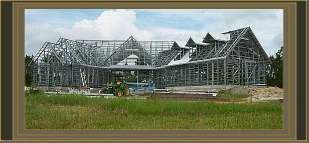 a large house is being built in a field with a tractor in the foreground .