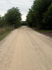 Gravel road stretching into the distance between green trees under an overcast sky