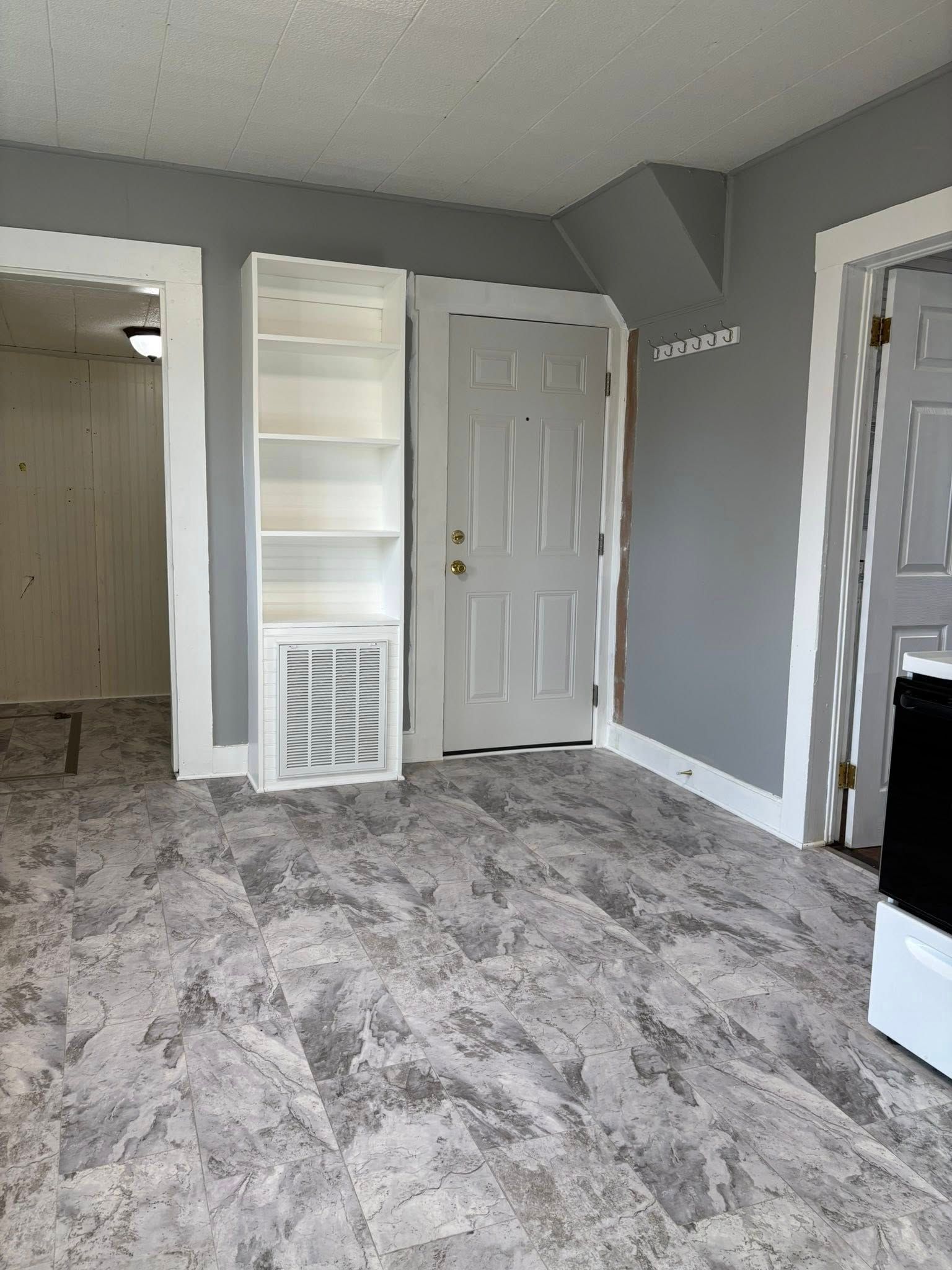 Interior of room with grey walls, white trim, open shelving, and a doorway.