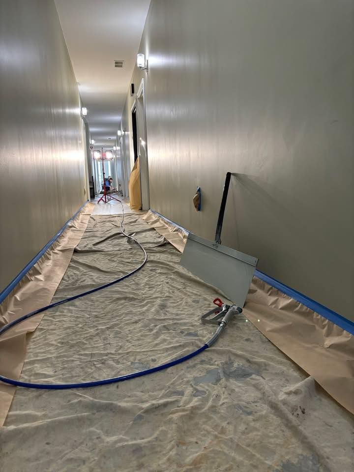 Hallway with painting supplies set up, covered with drop cloths and tape.