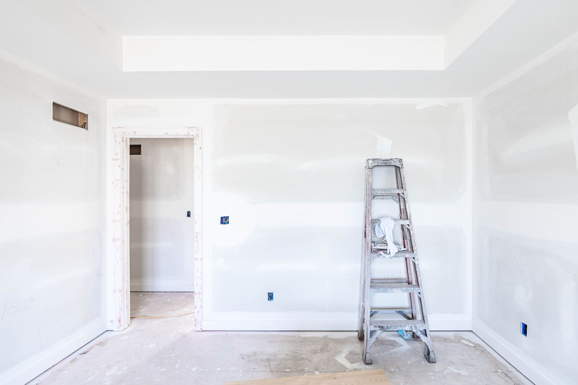Interior room with unfinished drywall, a ladder, and an open doorway.