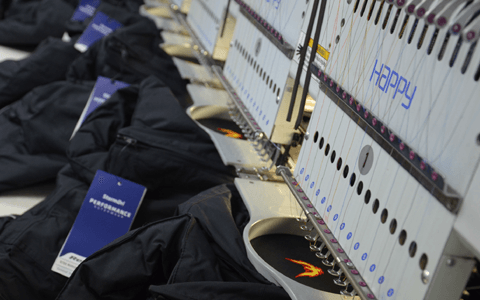 a row of jackets being embroidered by machine