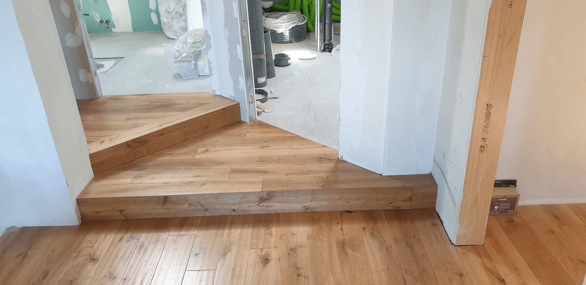 Pavimento in legno con scale e porta.