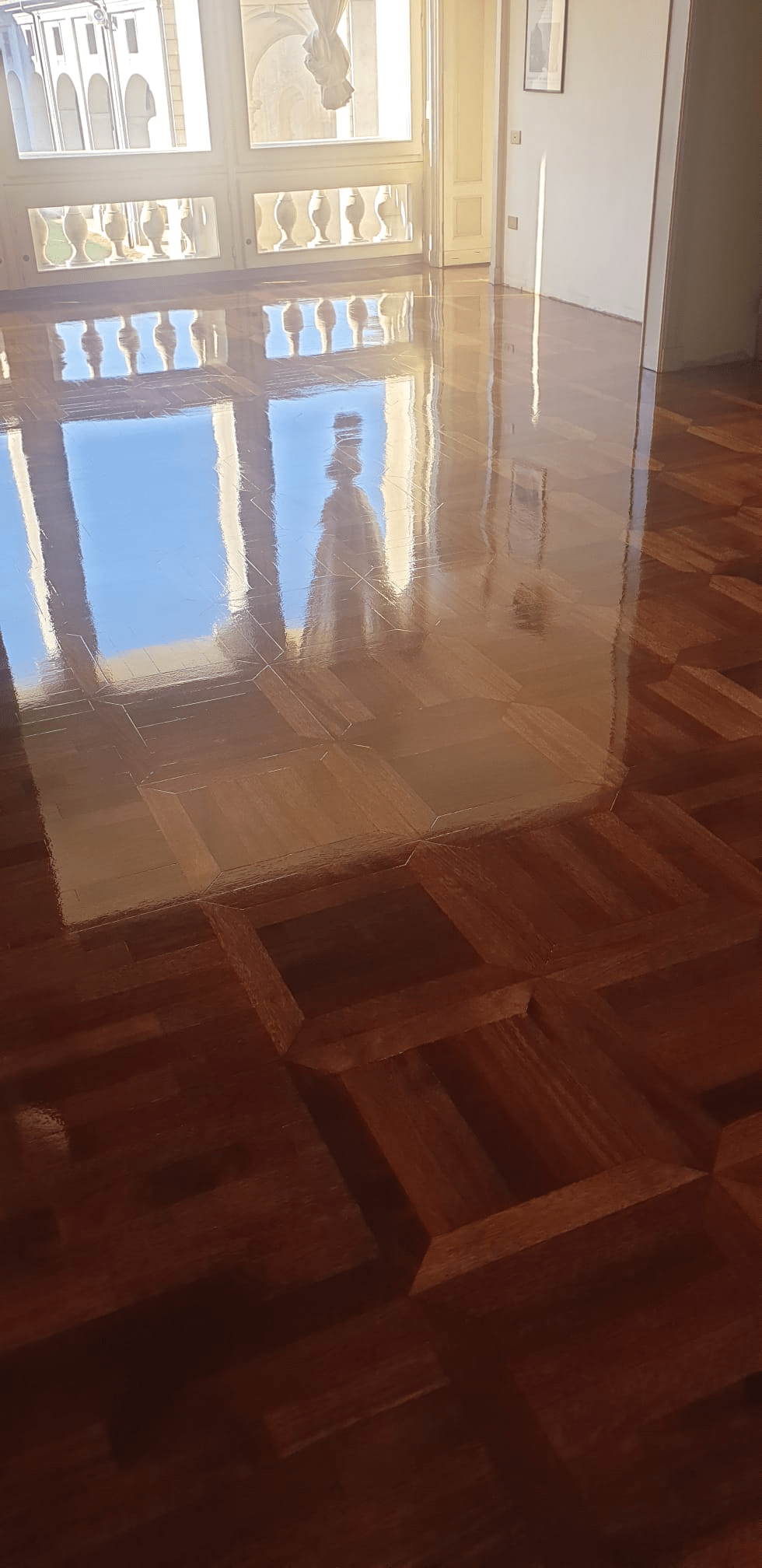 Pavimento riflettente con cielo blu e struttura bianca.