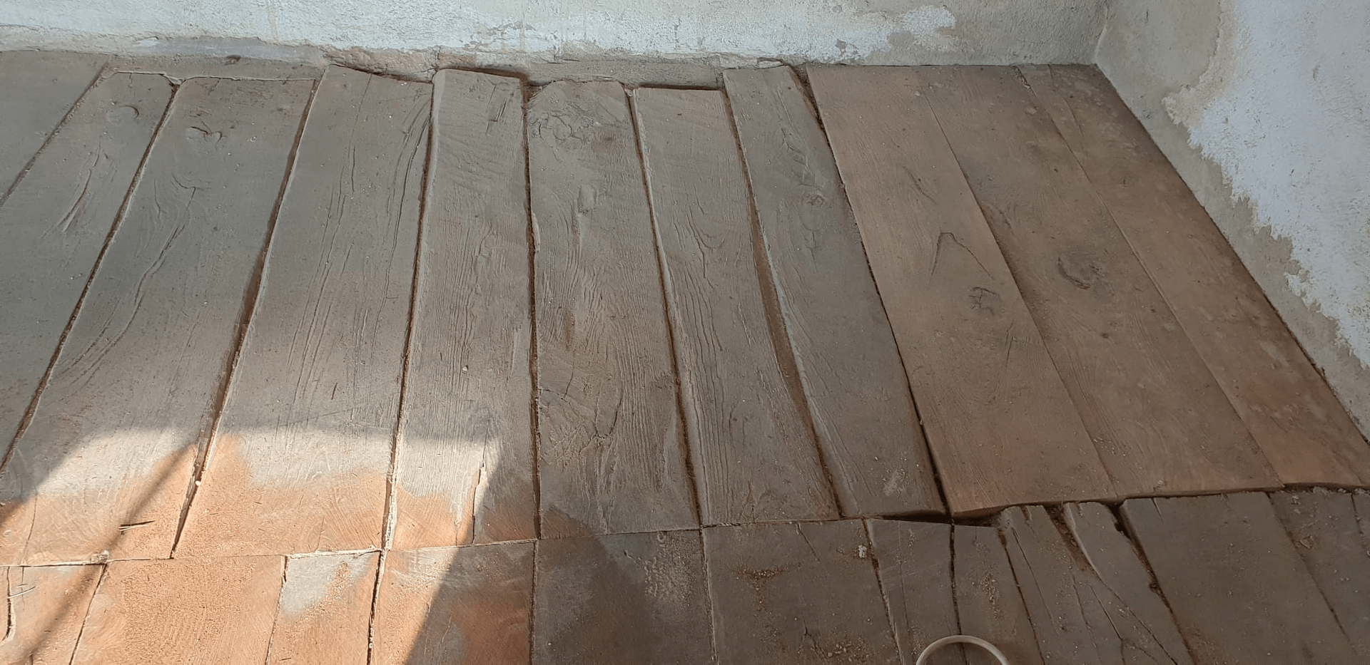 Vecchie assi di legno consumate in una stanza. Le assi sono irregolari e screpolate, con la luce del sole visibile.