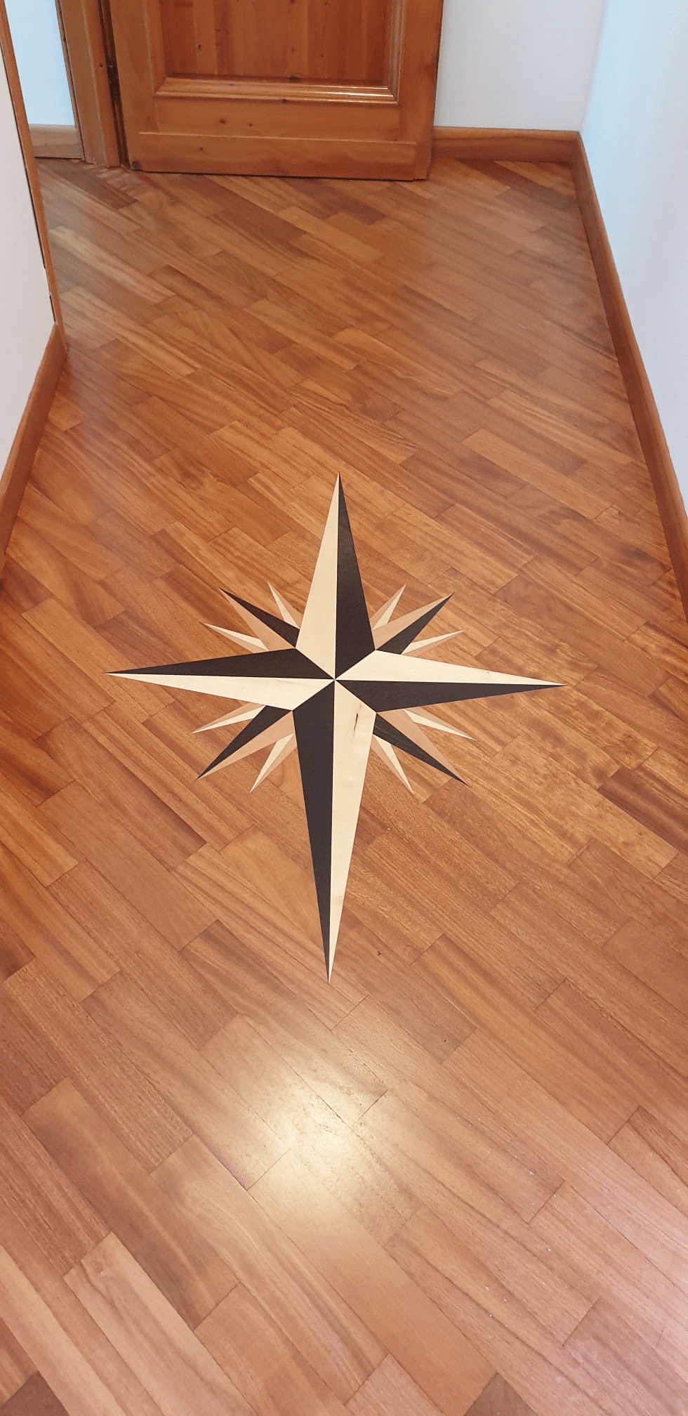 Pavimento in legno con intarsio raffigurante una rosa dei venti.