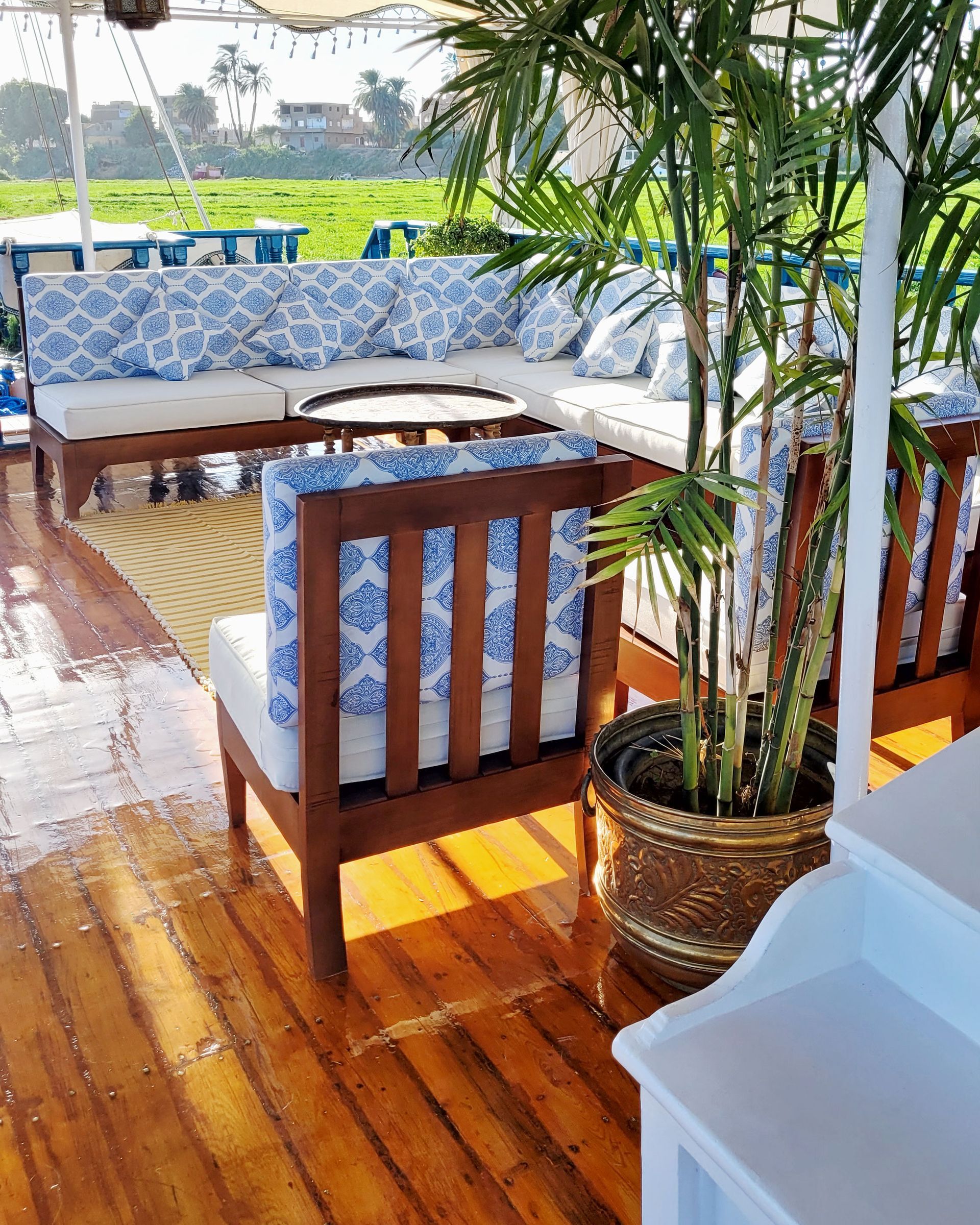 A photo of a cozy seating area on the deck of a traditional Egyptian sailing boat, the Dahabiya Kingfisher, which offers private cruises along the Nile river between Luxor and Aswan.