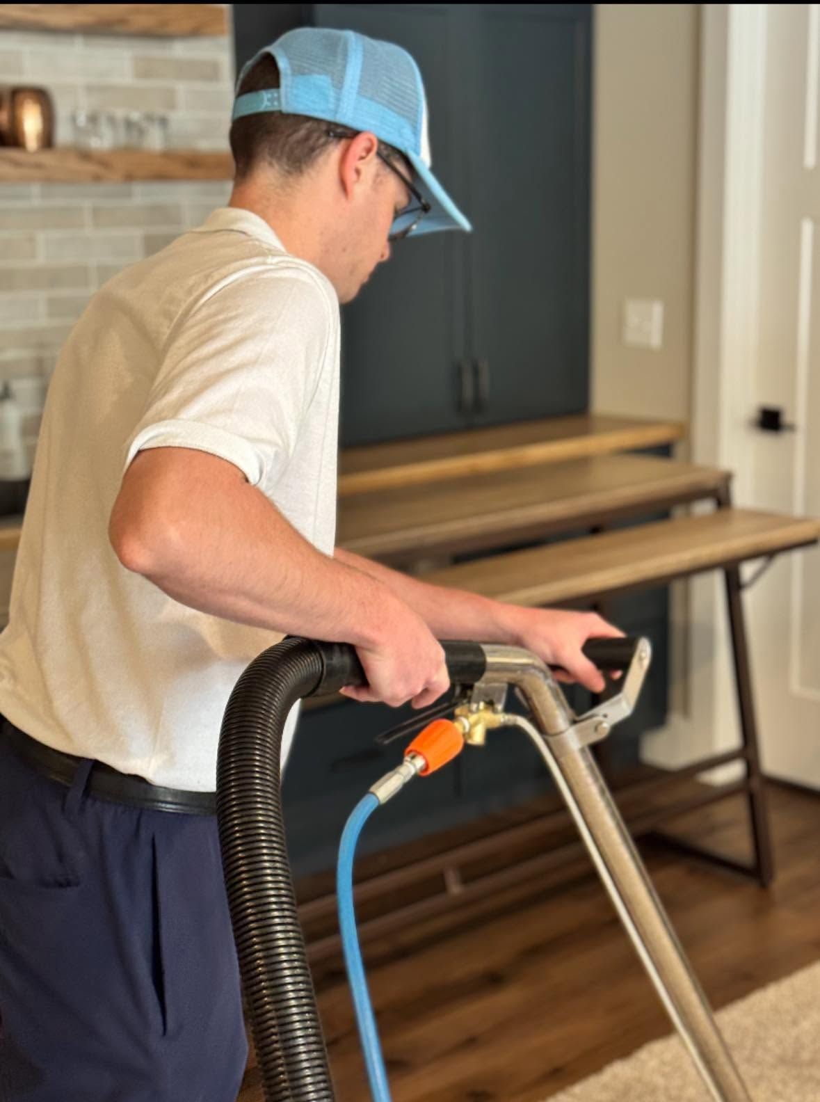 Person vacuuming hardwood floor beside a table in a living room