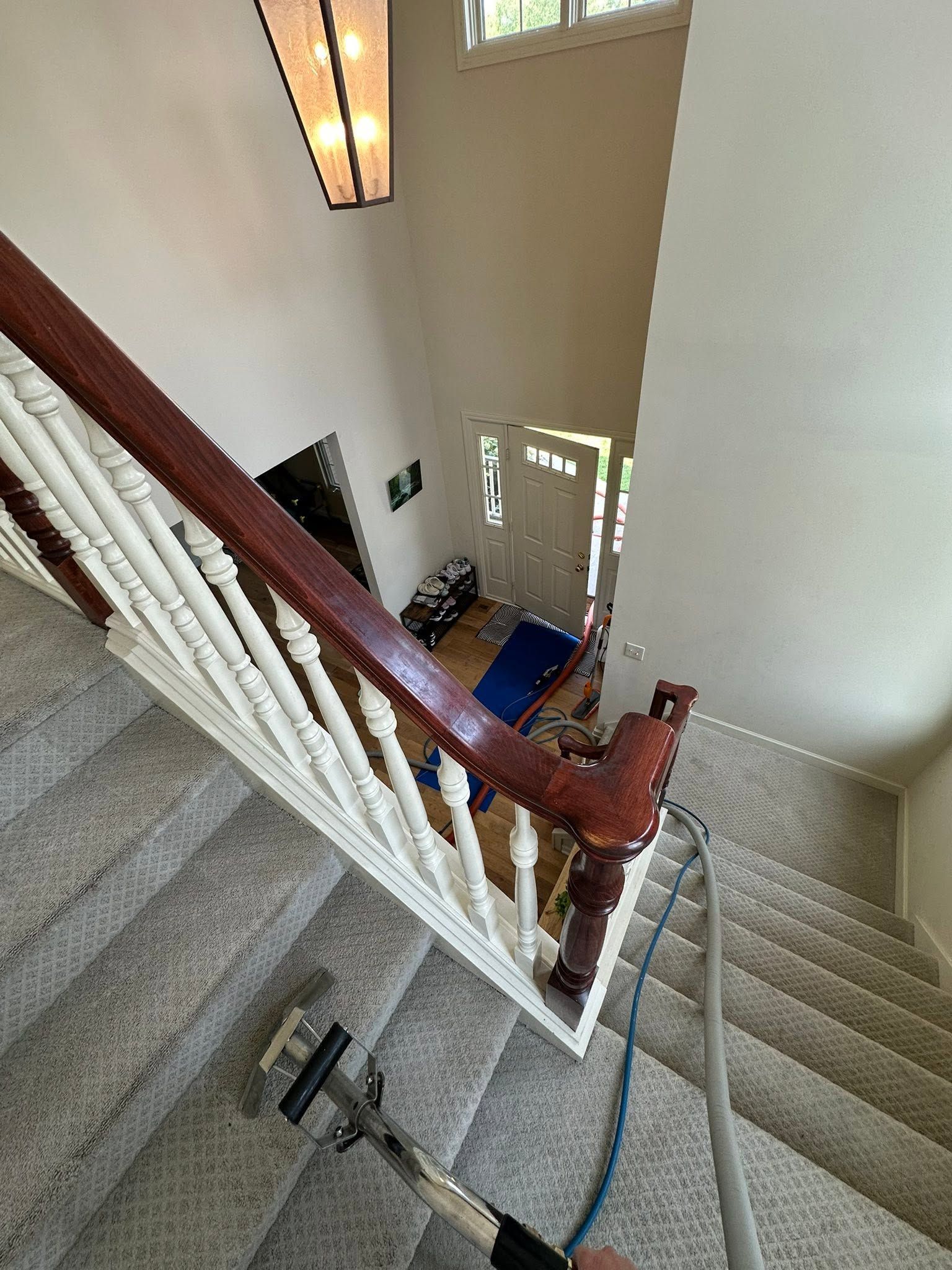 Carpeted staircase with wooden banister, white spindles, and a blue mat at the landing.