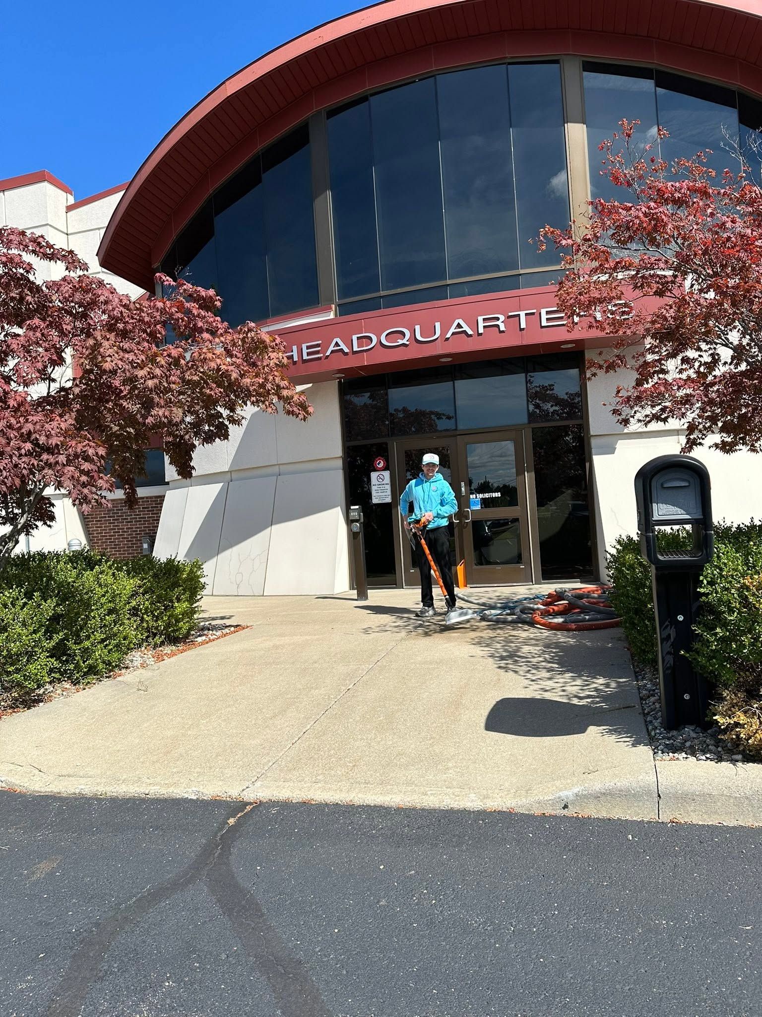 Person entering a building with a red arched roof and cherry blossoms outside