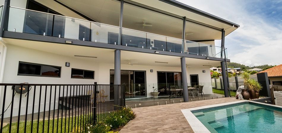 Modern two-story house with a balcony and black fence beside a swimming pool