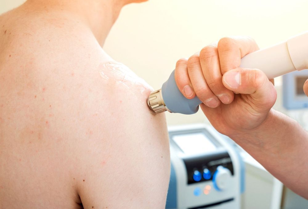 A man is getting an ultrasonic treatment on his shoulder.