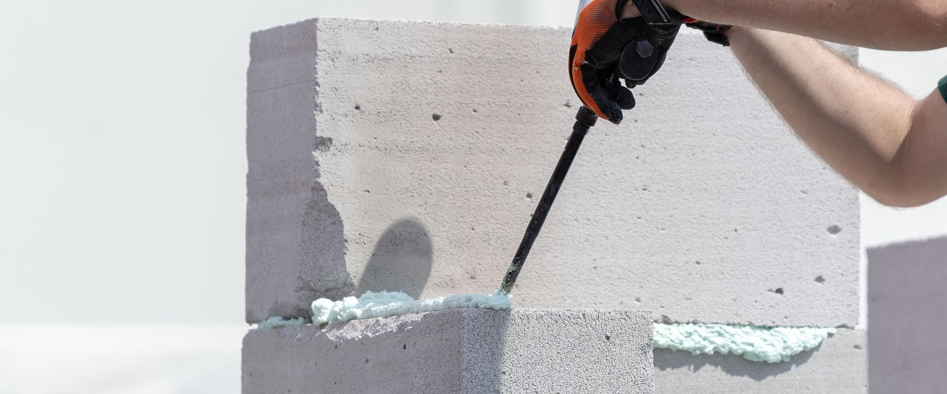 A person is spraying foam on a concrete block.