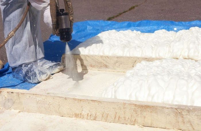 A person is spraying foam on a piece of wood.