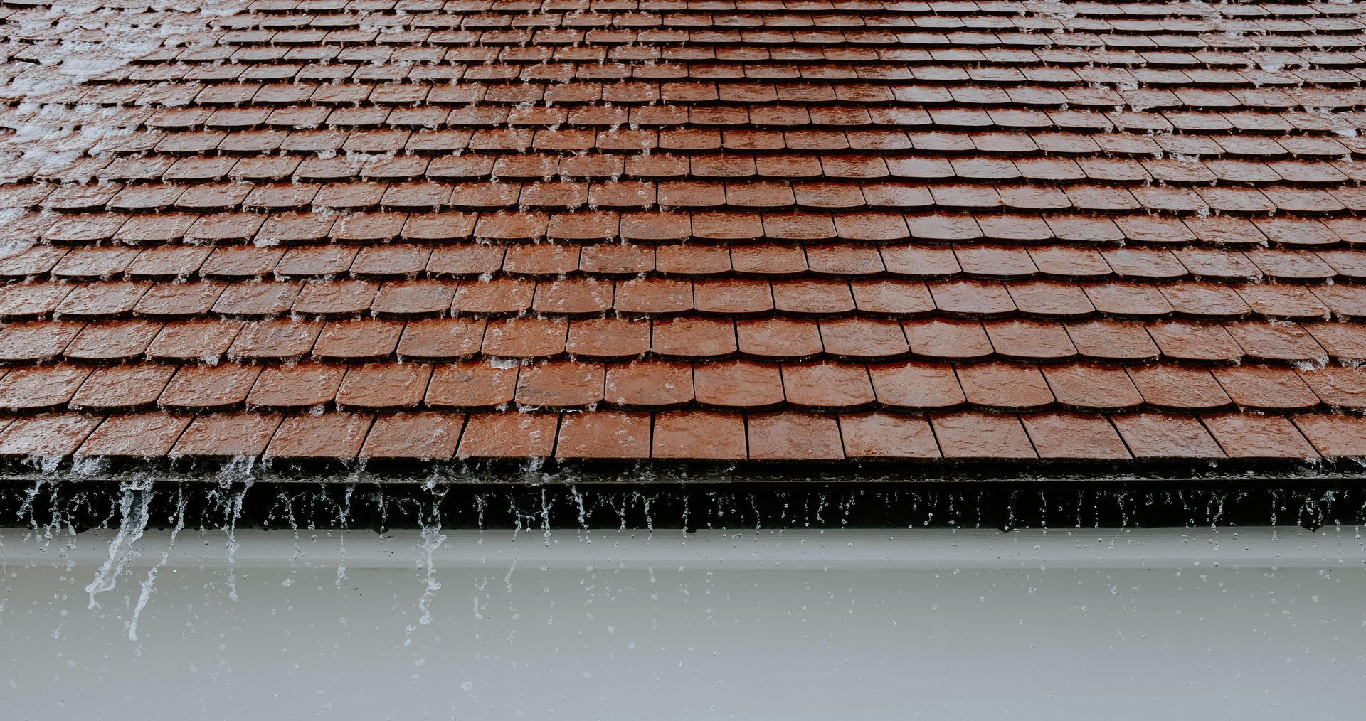 A person is cleaning a tiled roof with a high pressure washer.