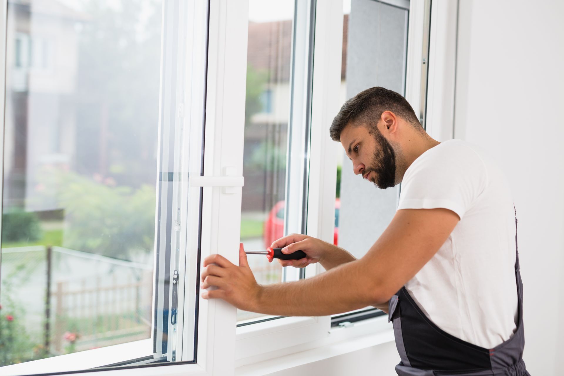 Technician adjusting and repairing a modern window frame with a screwdriver.
