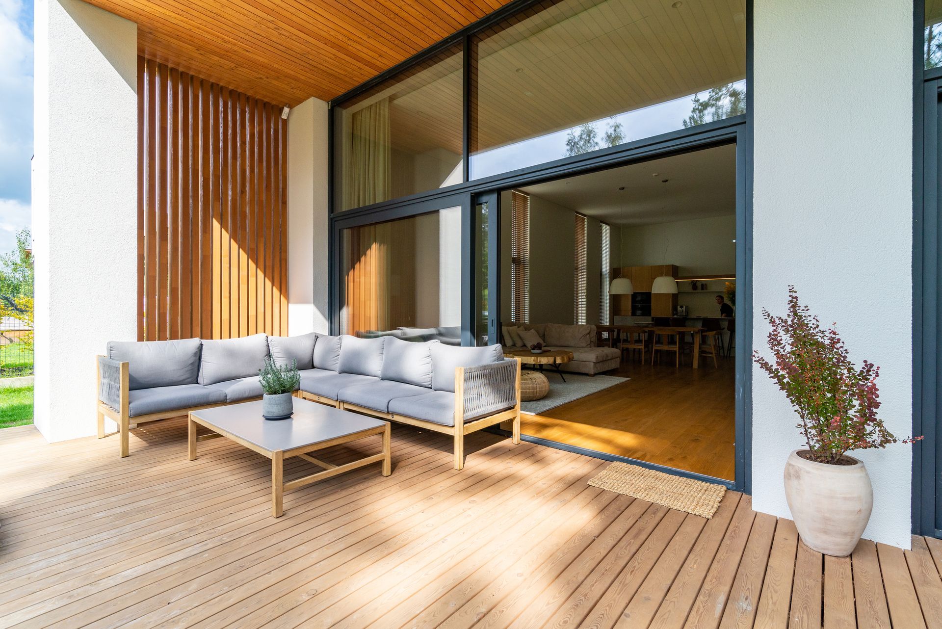 A modern patio with a gray sectional sofa, a coffee table, and a wooden deck.