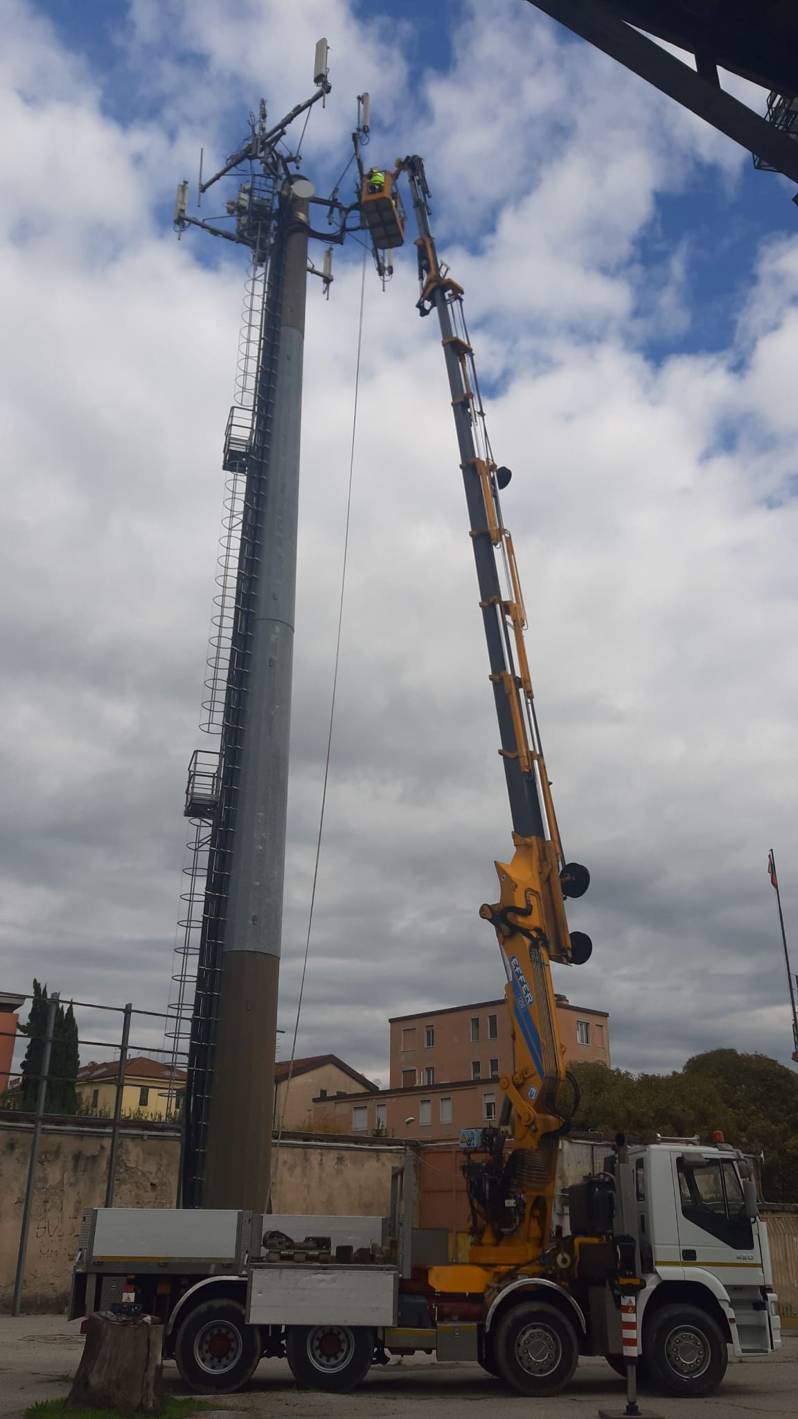 Un camion con una gru attaccata sta lavorando su un palo del telefono.