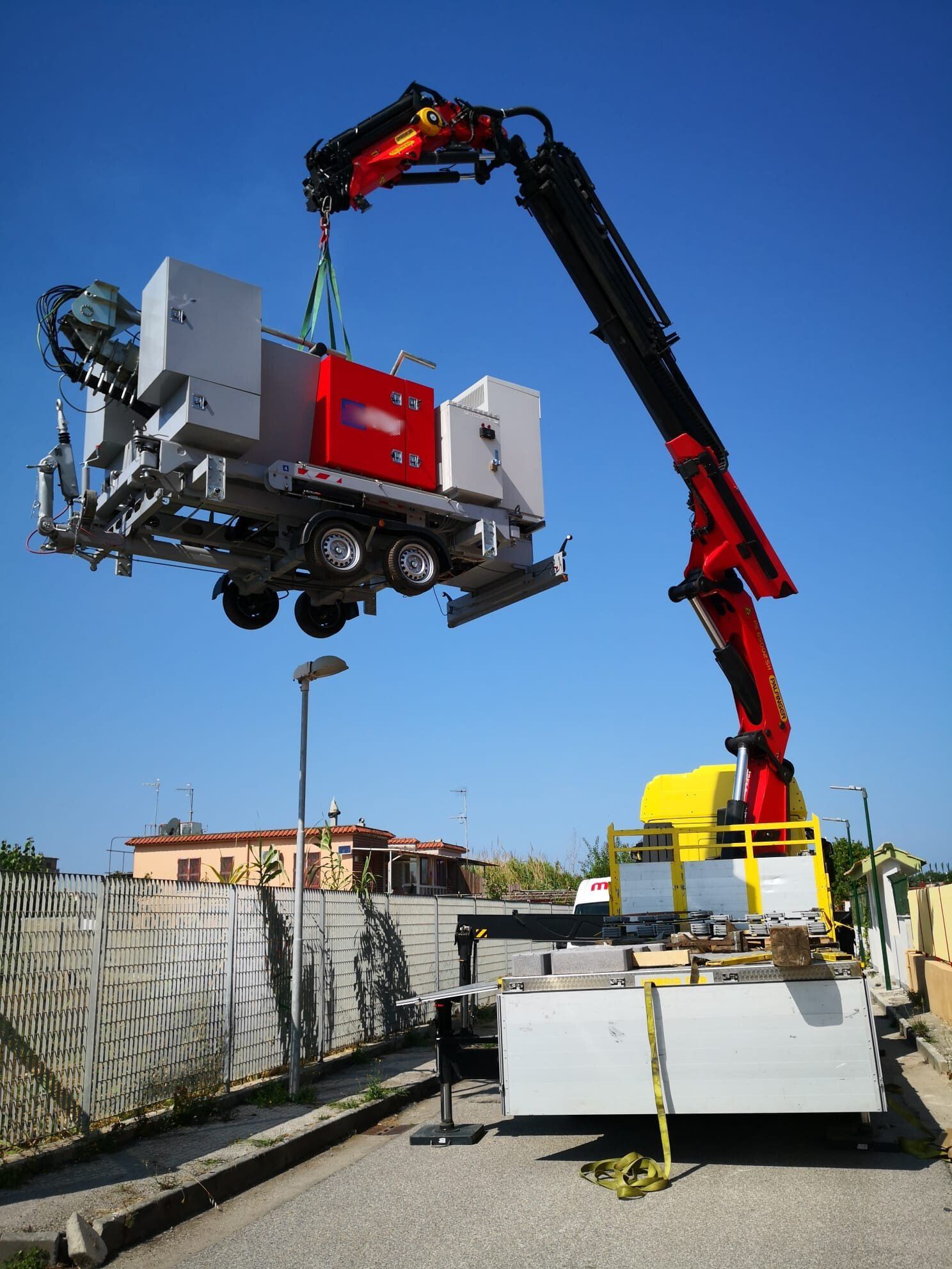 Una gru sta sollevando un rimorchio con delle scatole sopra
