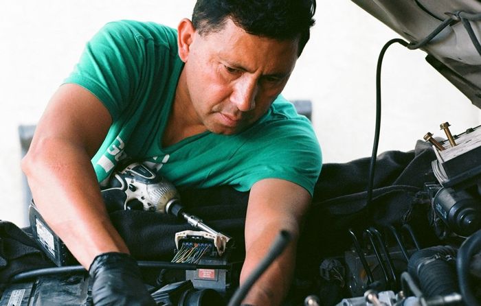 Un uomo sta lavorando sul motore di un'auto.