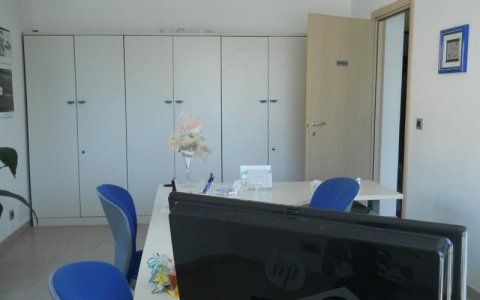 Una stanza con una scrivania, sedie e una tv