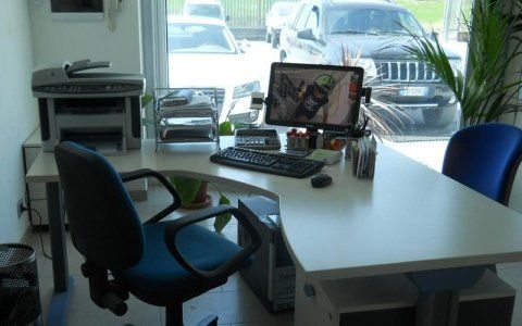 Una scrivania bianca con un computer e una sedia blu