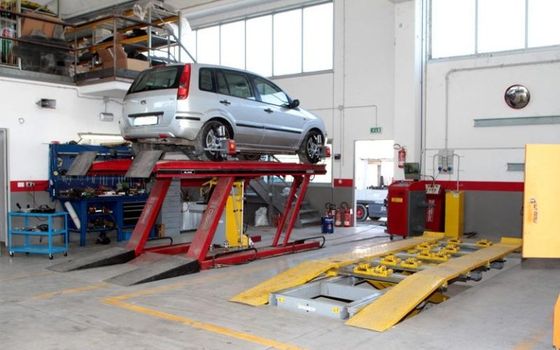 Un'auto è parcheggiata su un ponte sollevatore in un garage.