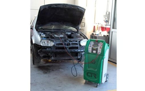 Un'auto con il cofano aperto è in manutenzione in un garage.