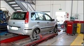 Un'auto grigia è parcheggiata su un ponte elevatore in un garage.
