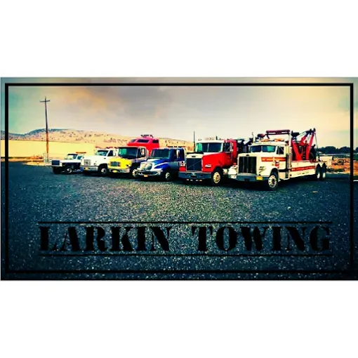 A line of various tow trucks parked in a gravel lot under a sky at dusk, with the text LARKIN TOWING overlaid below.