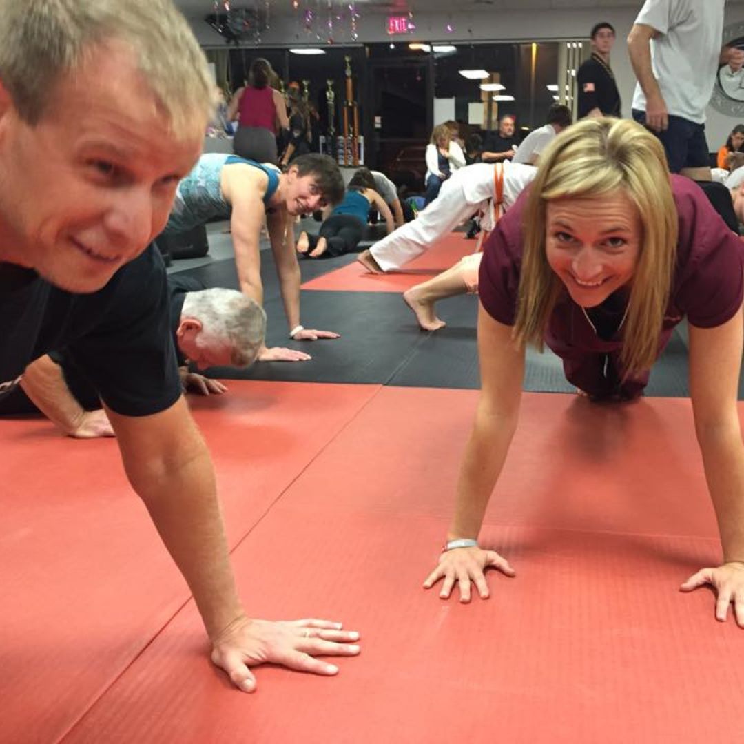 A woman is doing sit ups on a yoga mat in a gym.
