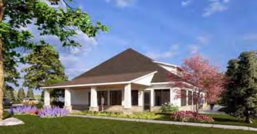 A single-story building with a dark roof and a covered porch, set in a landscape with green grass and blooming trees.