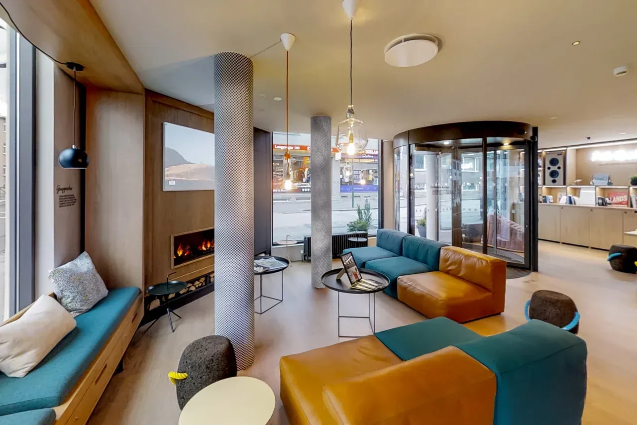Hotel lobby with teal and tan seating, fireplace, and revolving door entrance.