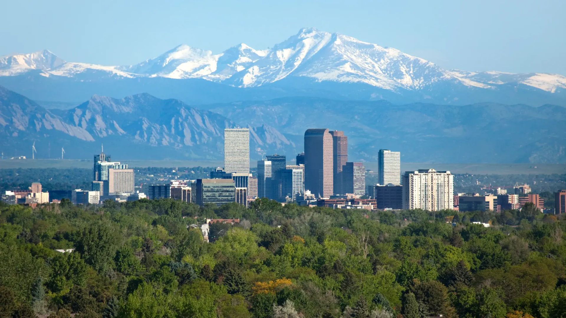Denver, Colorado skyline against a cloudy sky, seen from a snowy field.